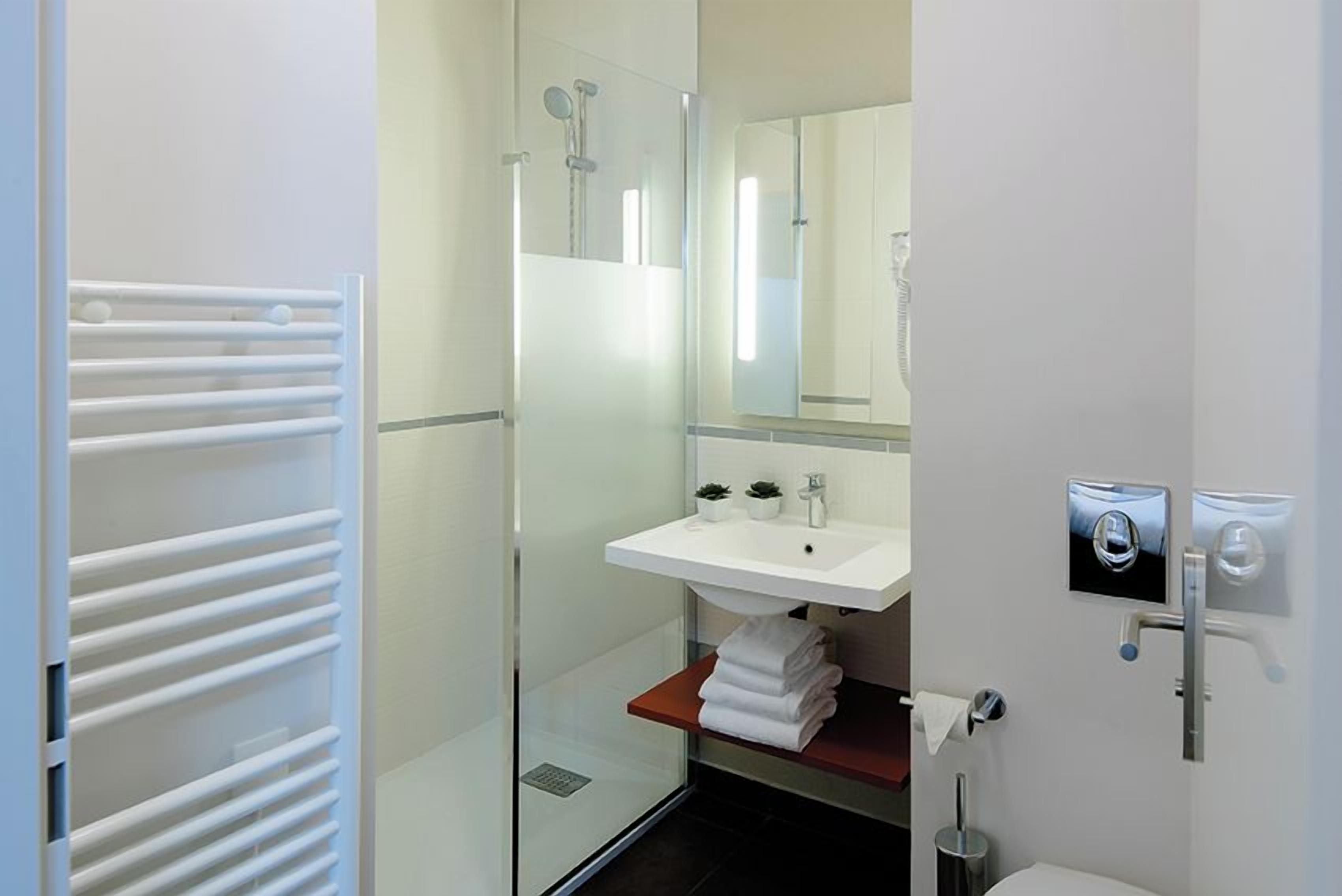 Une salle de bain moderne avec une douche à parois de verre, un lavabo blanc et un porte-serviettes.