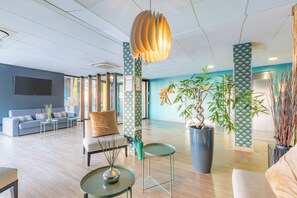 Een moderne lobby met een bank, salontafel en potplanten.