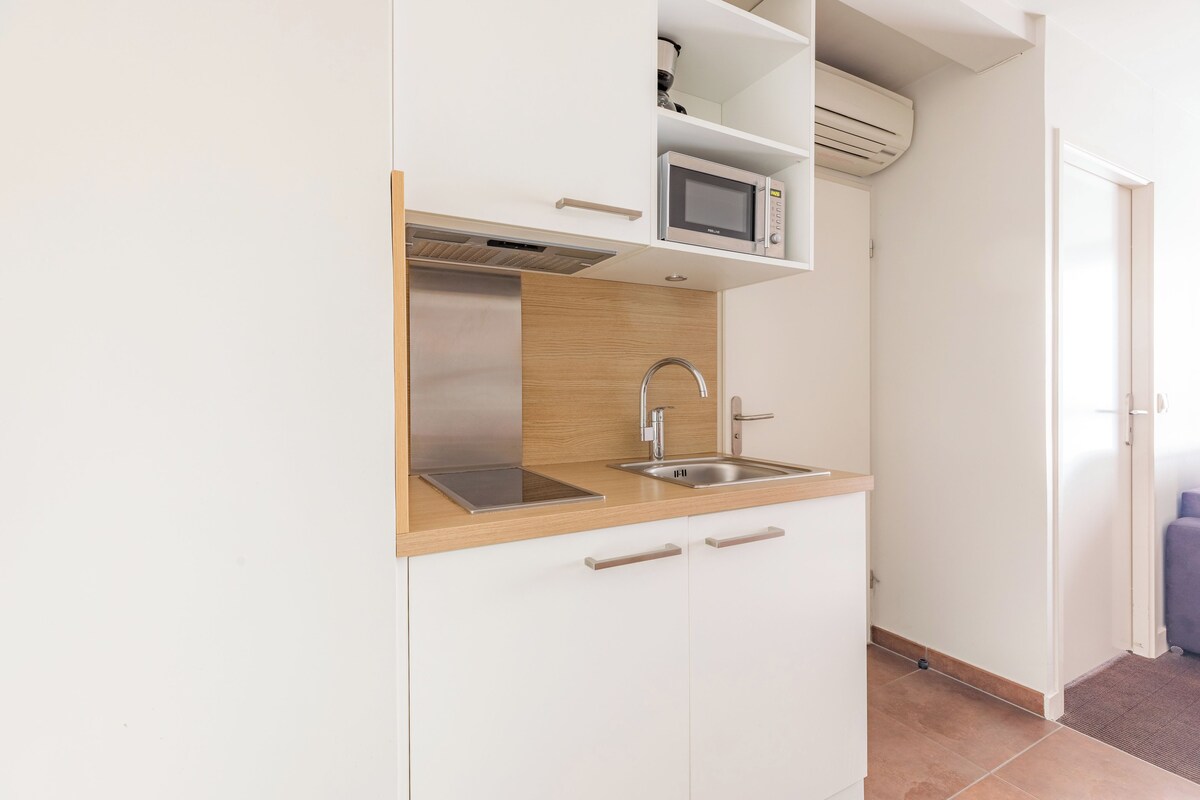 Een kleine keuken met een magnetron, een roestvrijstalen spoelbak en een houten aanrecht.