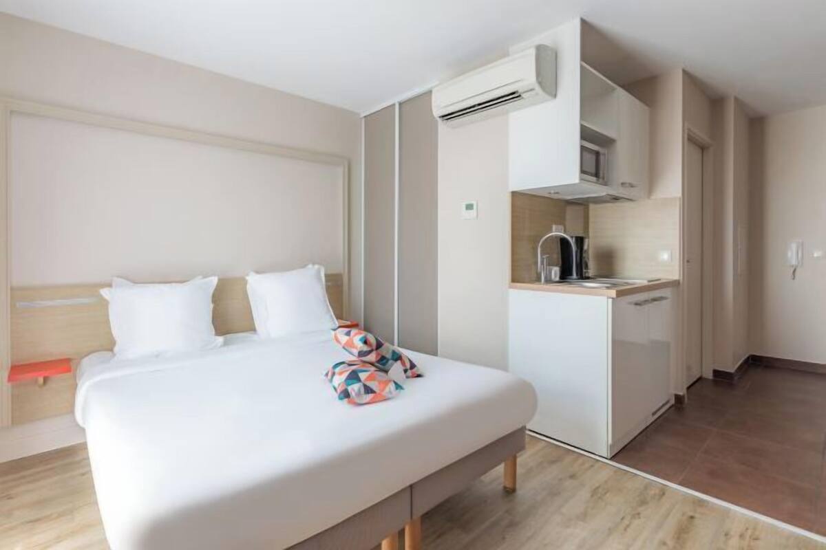 Een hotelkamer met een bed, een kitchenette en een airconditioner.