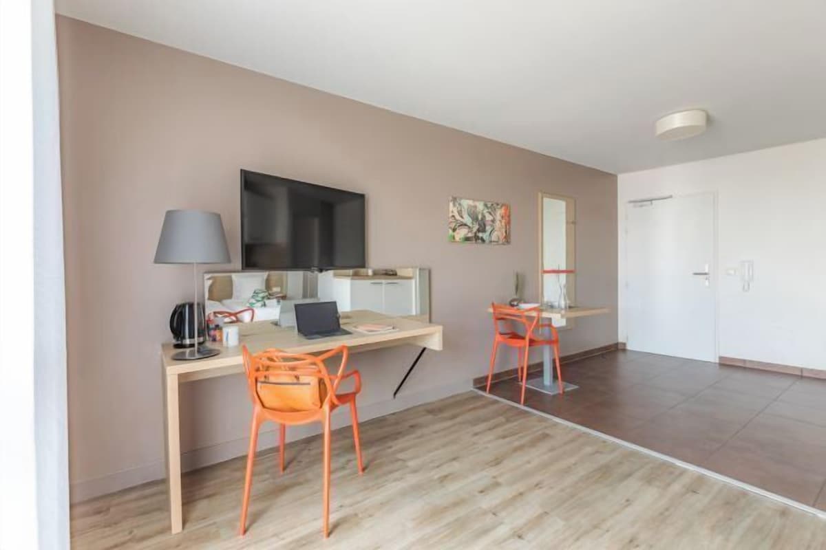 A modern room with a desk, two chairs, a television, and a mirror.