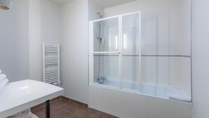 A modern bathroom with a glass-enclosed shower, a white sink, and a towel rack.