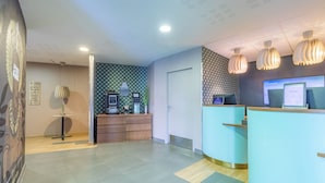 A reception area with a counter, a small table with a plant, and a wall with a geometric pattern.