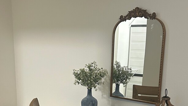 Un coin repas avec une table bleue, une chaise, un vase de fleurs, une bougie et un magazine.