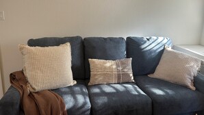 A dark blue sofa with three beige pillows and a brown throw blanket. - Charming 1-bedroom condo in welcoming Tallahassee with WiFi, AC (Tallahassee)
