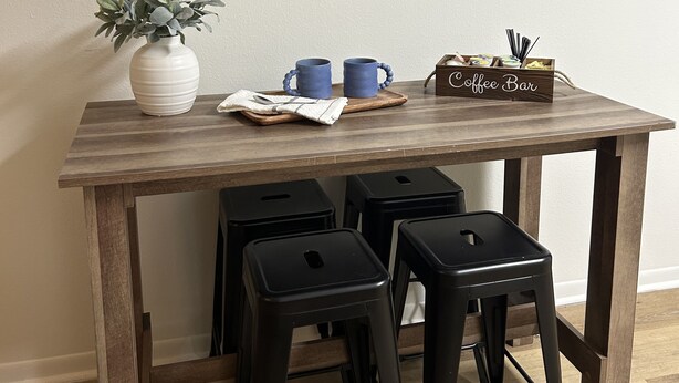 A wooden table with a coffee-themed decor, including a 'Coffee' sign, a coffee bar, and a potted plant. - Charming 1-bedroom condo in welcoming Tallahassee with WiFi, AC (Tallahassee)