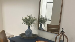 A blue desk with a mirror, two vases, a candle, and a magazine. - Charming 1-bedroom condo in welcoming Tallahassee with WiFi, AC (Tallahassee)