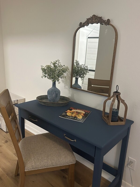 A blue desk with a mirror, two vases, a candle, and a magazine.