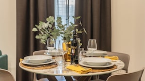 A dining table set with plates, glasses, a bottle, and a vase with greenery. - Rezia Apartments - Bellagio Suite (Como)