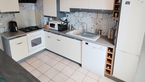 A modern kitchen with white cabinets, a gas stove, a microwave, and a refrigerator.