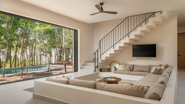 Ein modernes Wohnzimmer mit einem großen Fenster, einem Sofa, einem Couchtisch und einer Treppe.
