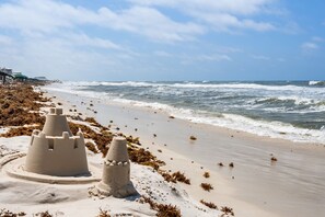 Une plage avec des châteaux de sable et des algues.