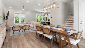 A modern dining area with a wooden table, chairs, and pendant lighting. - 3Zs Beach House 30A  Sleeps 10! (Inlet Beach)