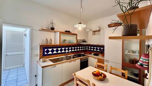 Eine kompakte Küche mit Essbereich, mit Fliesenrückwand, Holzausstattung und einer Obstschale auf dem Tisch.