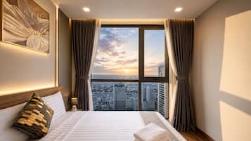 A hotel room with a large bed, a view of the cityscape through a window, and curtains.