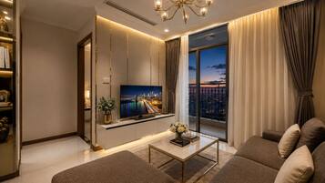 A modern living room with a television, sofa, coffee table, and a view of a cityscape through large windows.