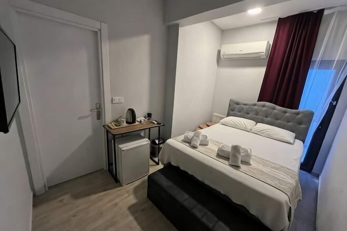 A bedroom with a bed, bedside table, and a small desk with a lamp.