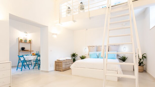 A modern, well-lit room with a bunk bed, a dining area with blue chairs, and a ladder leading to a loft. - Darsena Sunset Apartment I by Wonderful Italy (Syracuse)