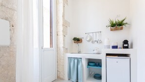 A compact kitchen with a white countertop, a sink, a small refrigerator, and a window with a view of the outside. - Darsena Sunset Apartment II by Wonderful Italy (Syracuse)