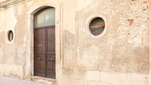A building with a large wooden door, two small circular windows, and a stone facade. - Darsena Sunset Attic by Wonderful Italy (Syracuse)