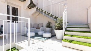 A modern outdoor living area with a white staircase, a seating area with cushions, and a potted plant. - Darsena Sunset Attic by Wonderful Italy (Syracuse)
