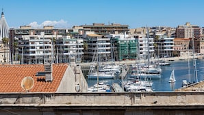 A marina with numerous boats docked, surrounded by multi-story buildings with balconies. - Darsena Sunset Attic by Wonderful Italy (Syracuse)
