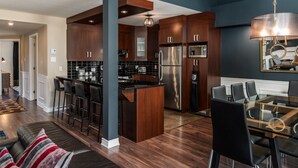 A modern kitchen with dark wood cabinets, stainless steel appliances, and a central island with bar stools.