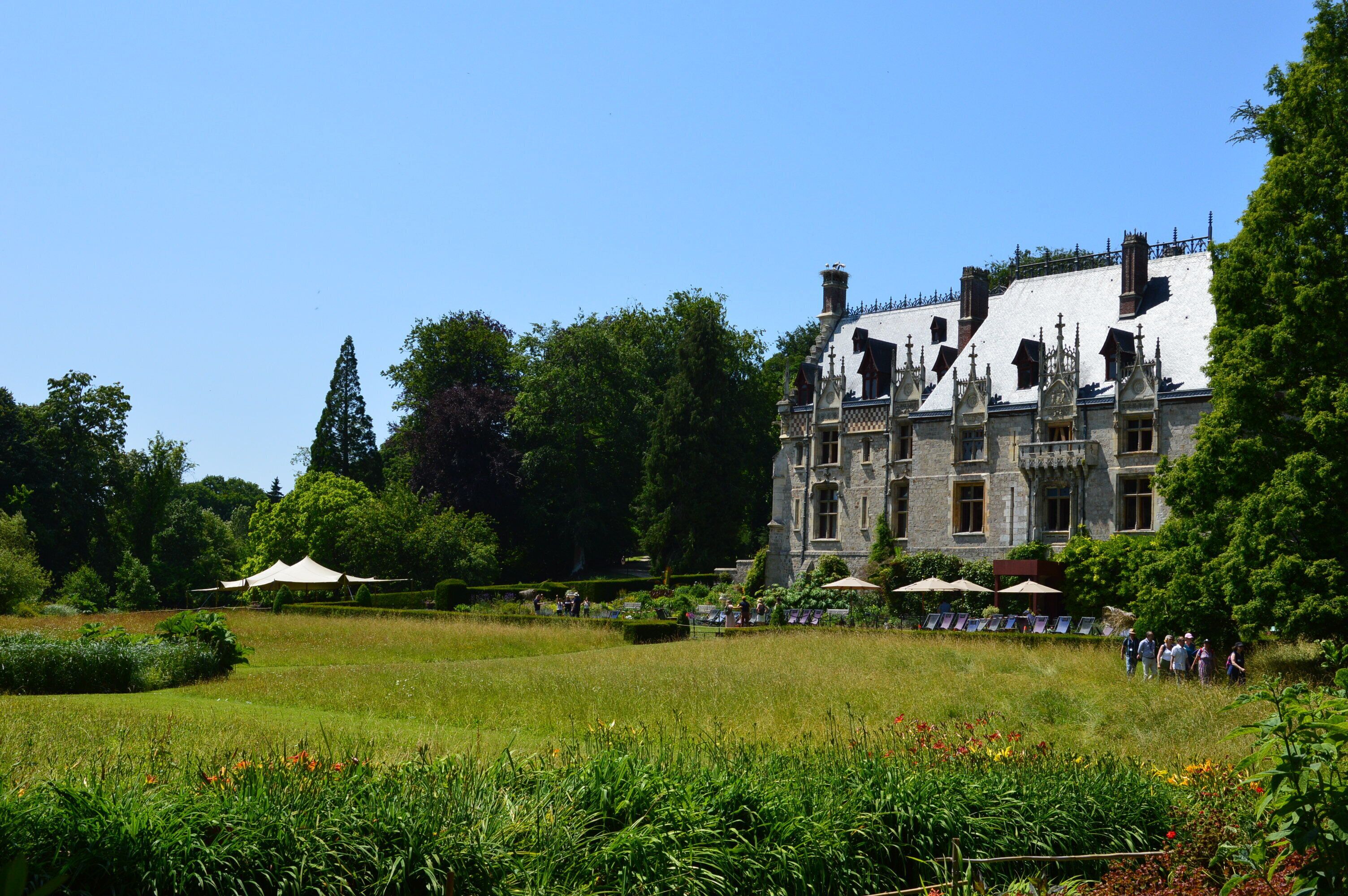A large, historic building with a well-maintained garden and outdoor seating area.