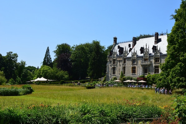 Un edificio grande e histórico con un jardín cuidado y un área de estar al aire libre.