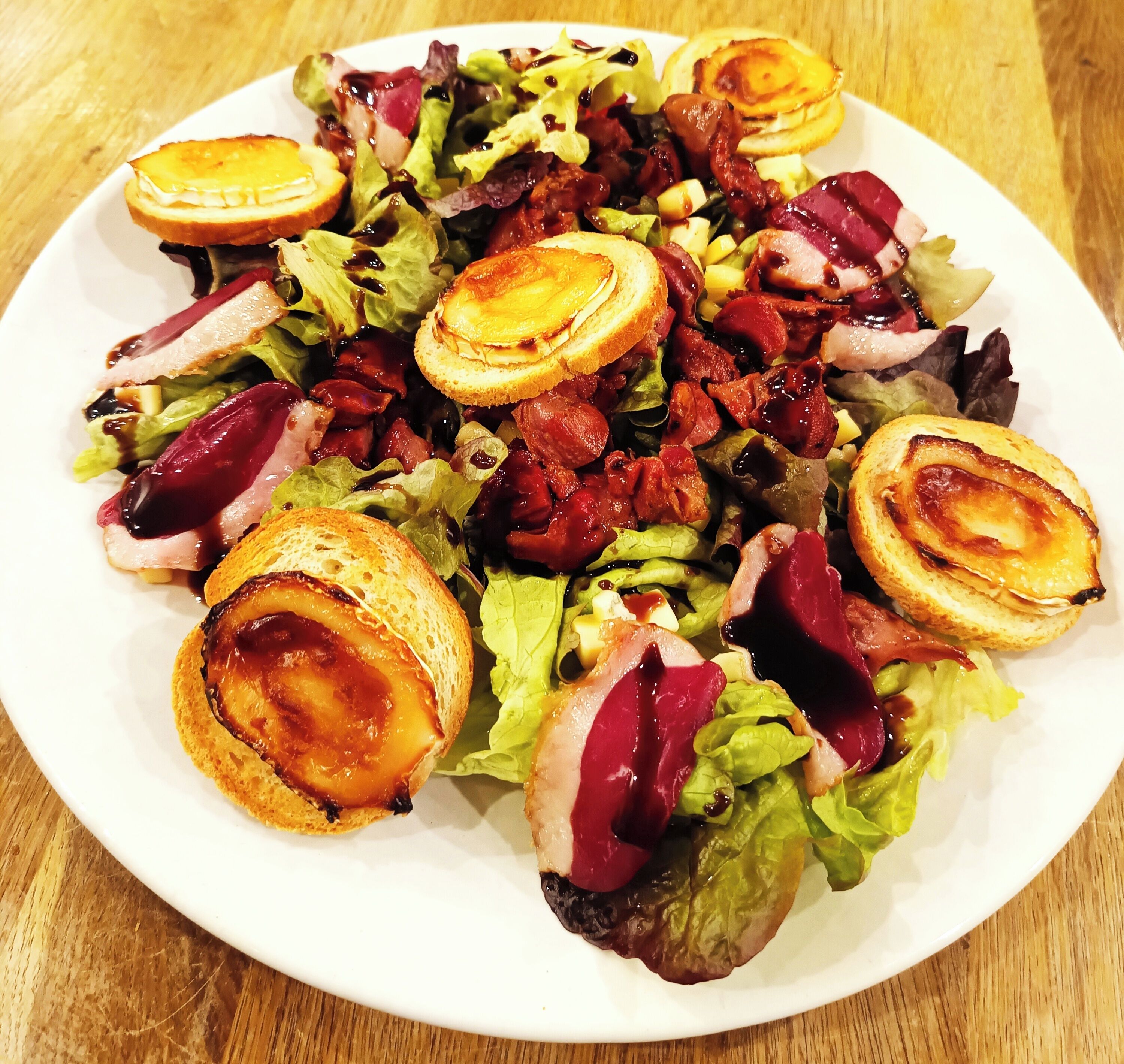 Een bord eten met geroosterd brood, vlees en salade.