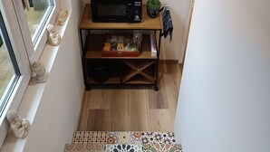 A room with a wooden desk, a red clock, and hanging plants.