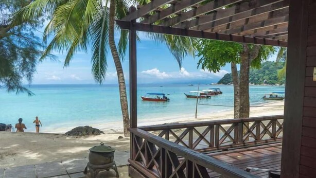 Une terrasse en bois offrant une vue sur la plage et l’océan.