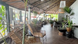 Un espace intérieur spacieux doté d’un plancher en bois, de différents coins salon et de plantes en pot.