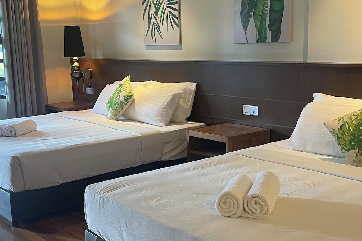 A hotel room with two beds, wooden flooring, and artwork on the walls.