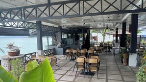 Un espace extérieur aménagé avec des tables et des chaises, une vue sur la mer et des plantes en pot.