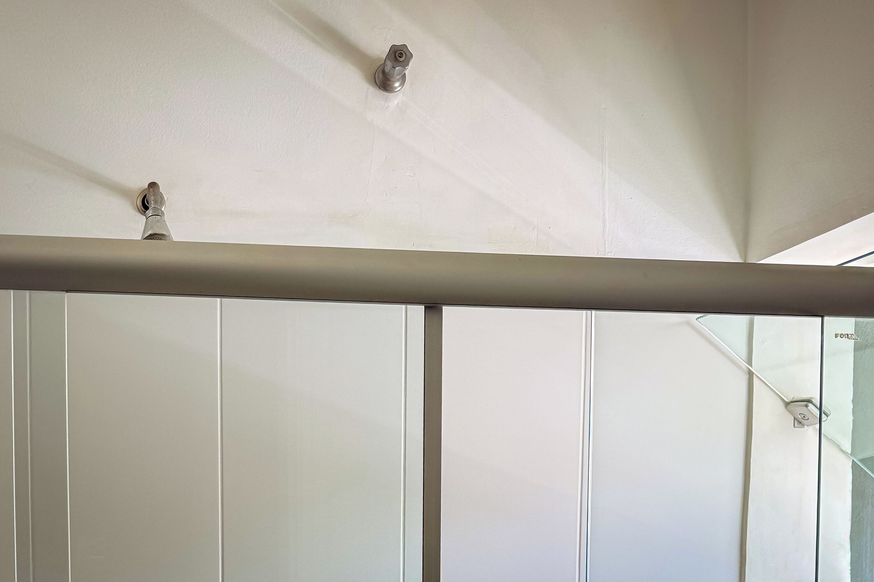 A white ceiling with two light fixtures and a metal bar across the room.