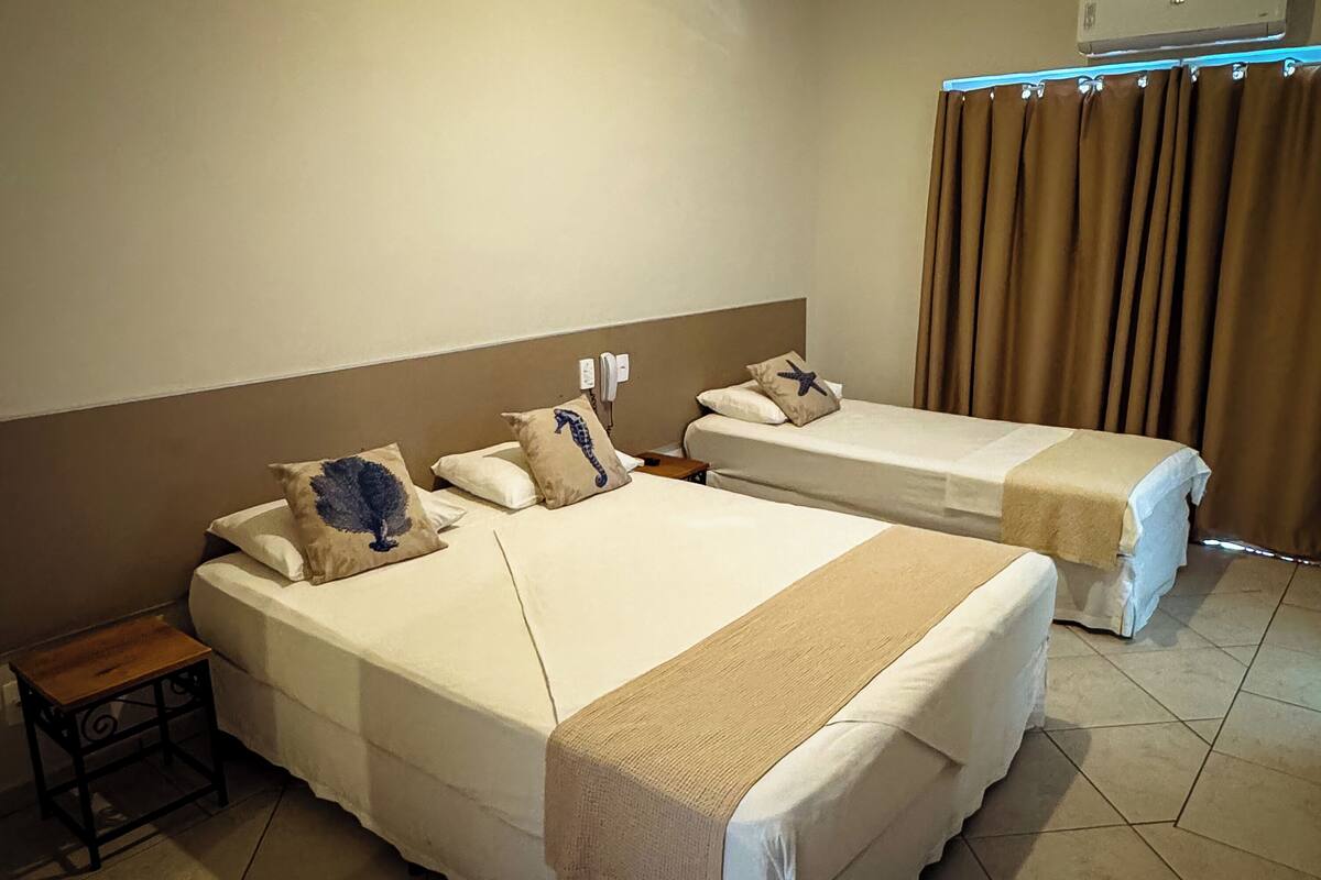 A hotel room with two beds, a small table, and a curtain.