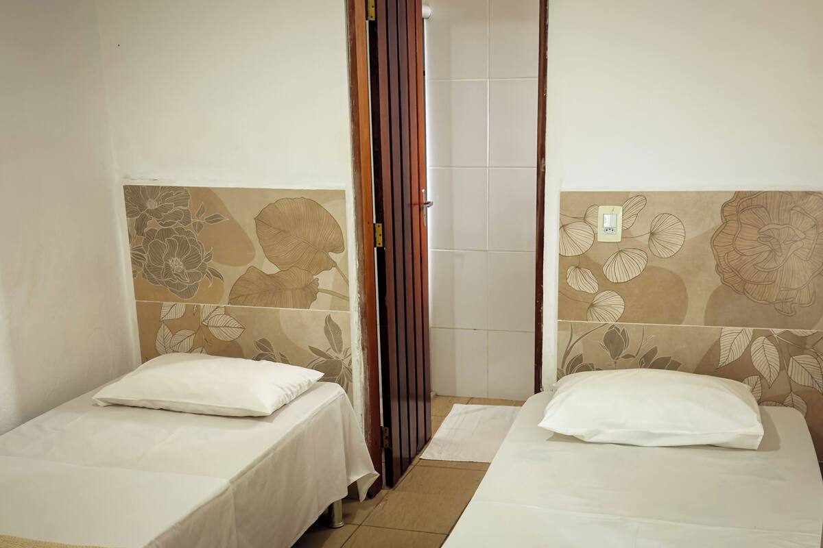 Two single beds with white bedding and floral-patterned headboards in a room with tiled walls.