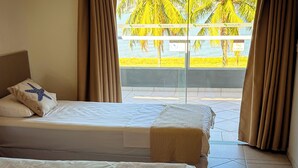 A hotel room with a bed, a window with curtains, and a view of palm trees. - VELINN Hotel Guarda Mor (São Sebastião)