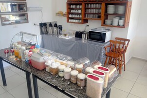 Een ontbijtbalk met diverse etenswaren en sauzen, een magnetron en een koffieapparaat.