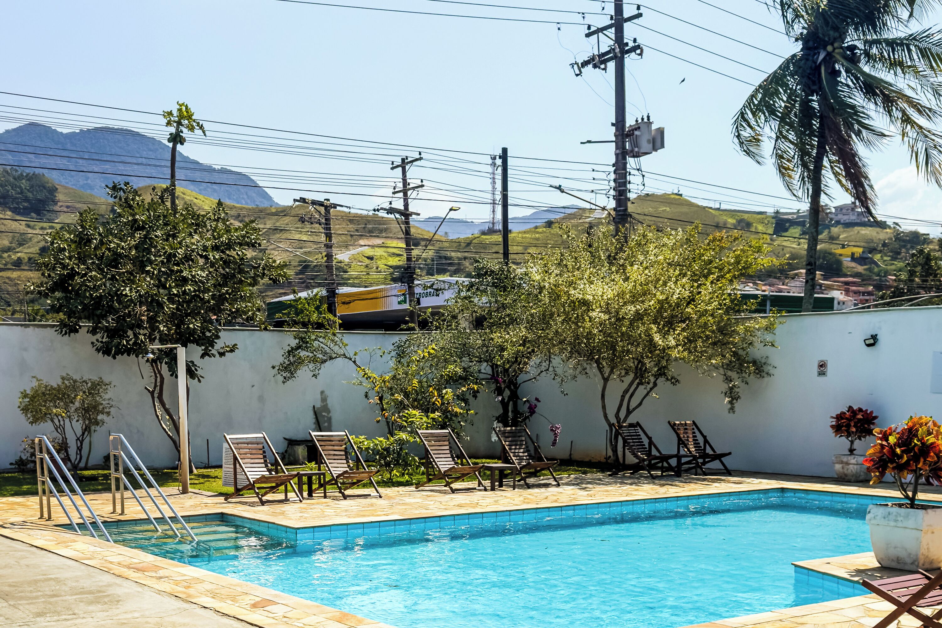 A swimming pool with lounge chairs and a view of hills in the background.