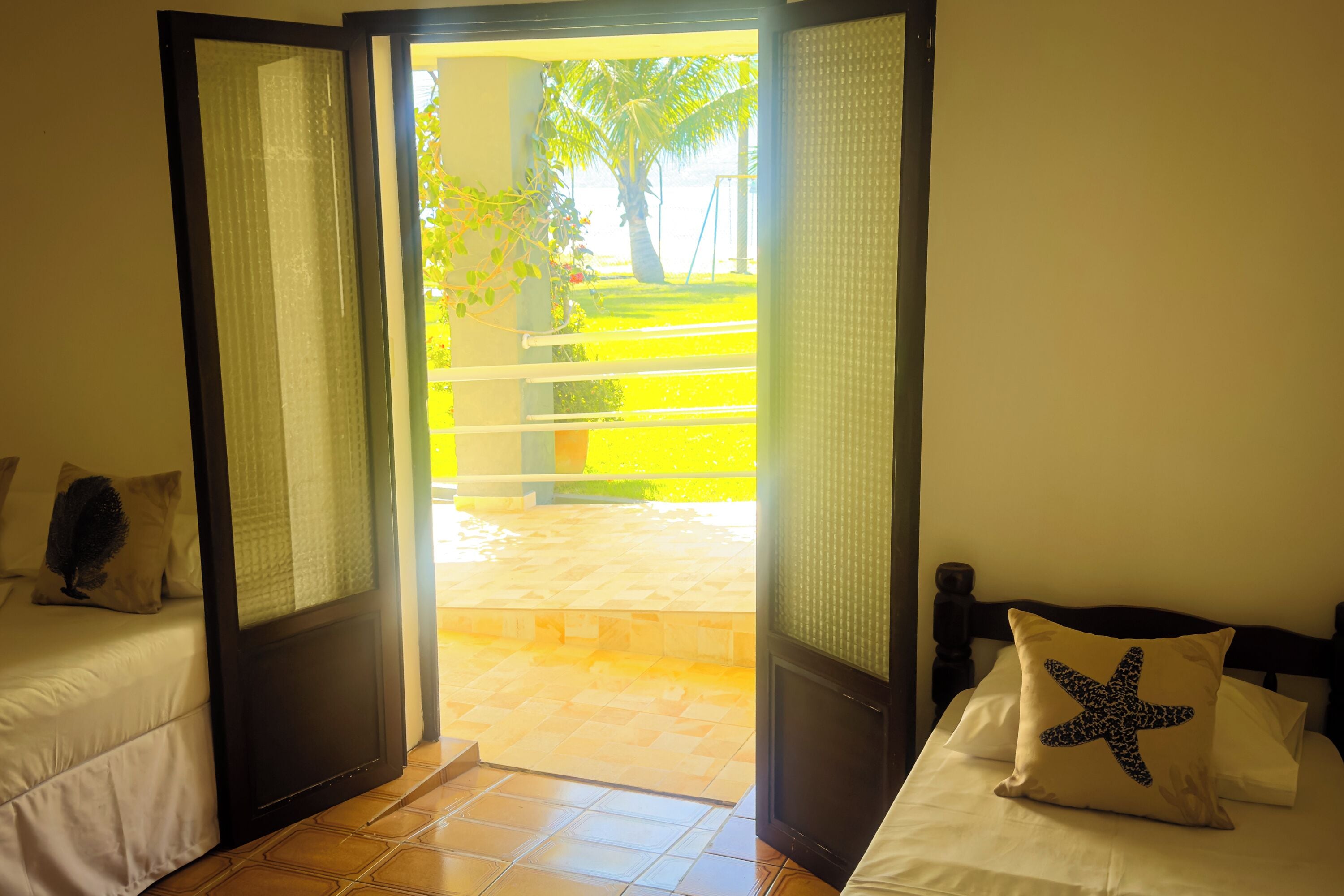 Una habitación con cama, ventana y vistas a un jardín.