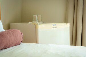 Een hotelkamer met een bed, een nachtkastje en een klein wit kastje met de tekst 'Consul'.