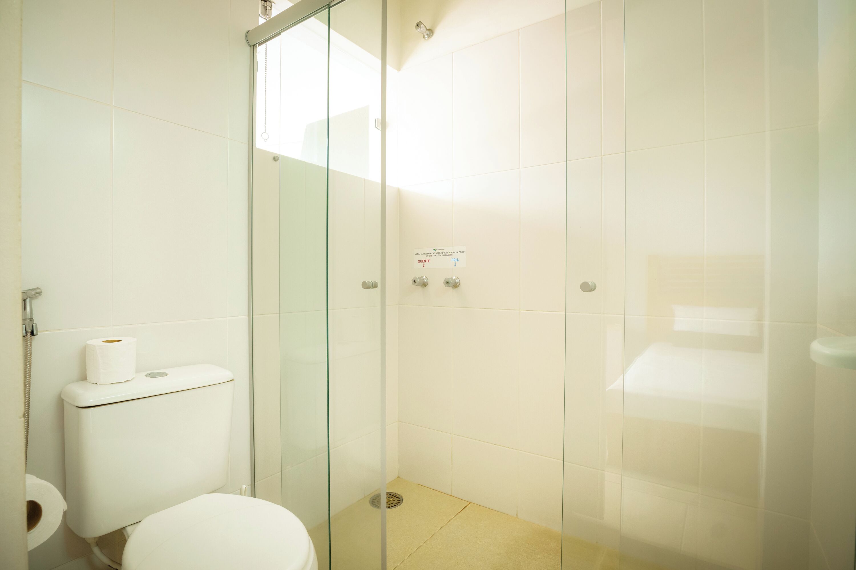 Un baño con inodoro, cabina de ducha de vidrio y panel de control en la pared.