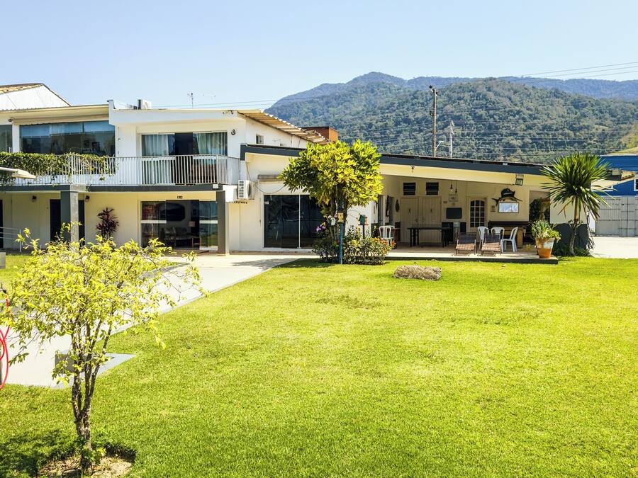 Una casa moderna de dos pisos amb un jardí ben cuidat, un patio amb mobles d'exterior i un paisatge de muntanya al fons.