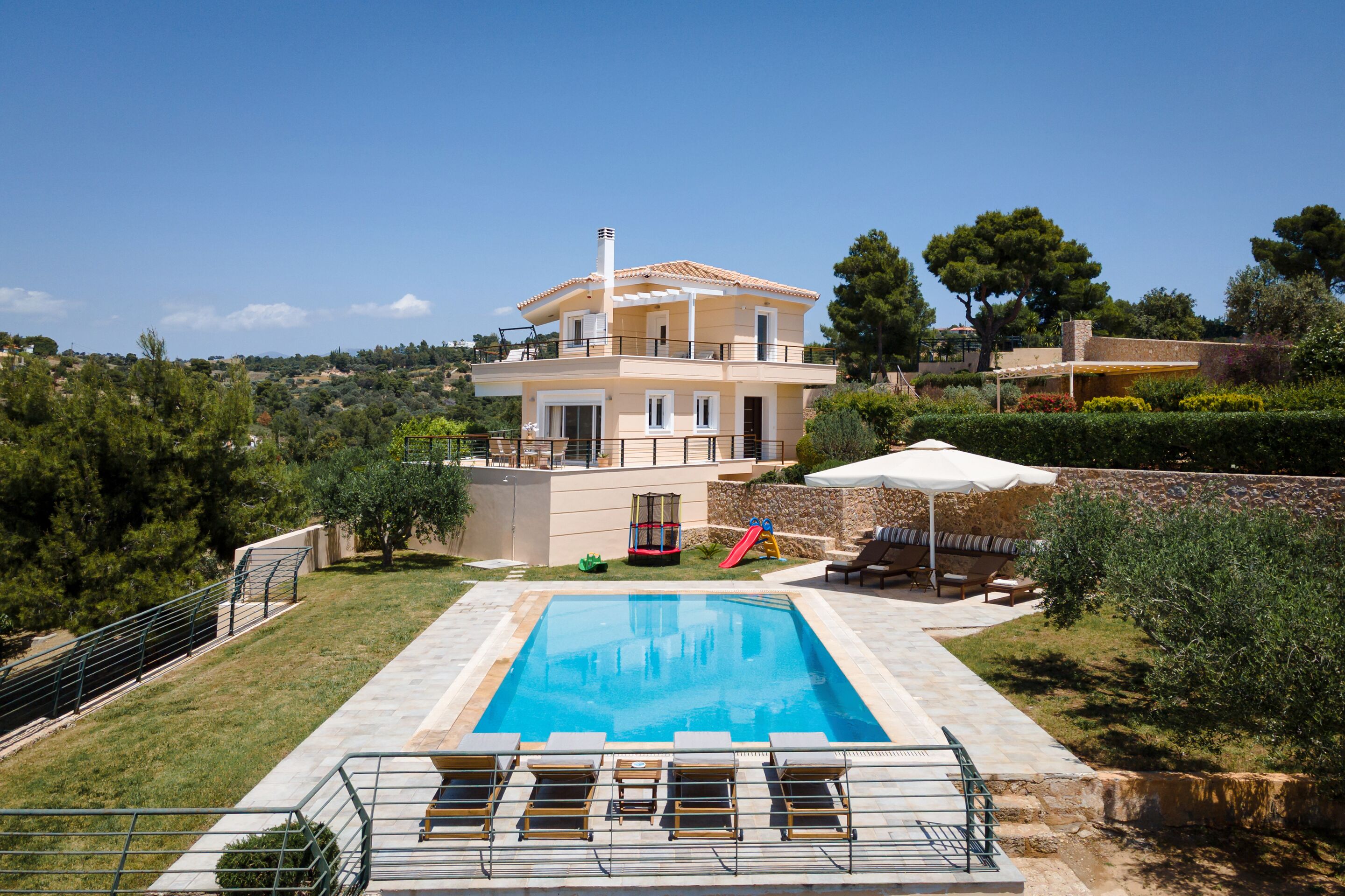 A two-story house with a swimming pool, outdoor seating, and a playground.