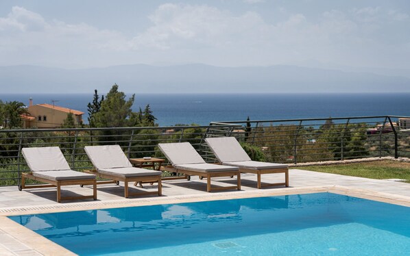 A pool with lounge chairs and a view of the sea. - Hegemoni Villa Porto Heli (Ermionida)