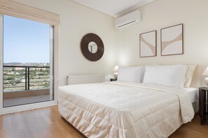 A bedroom with a large bed, a round mirror, and two framed artworks on the wall. - Hegemoni Villa Porto Heli (Ermionida)