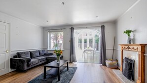 Ein geräumiges Wohnzimmer mit grauem Sofa, einem Couchtisch und einem Kamin.