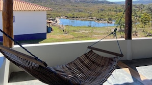 Una hamaca bajo una pérgola de madera con vista a un lago y colinas.